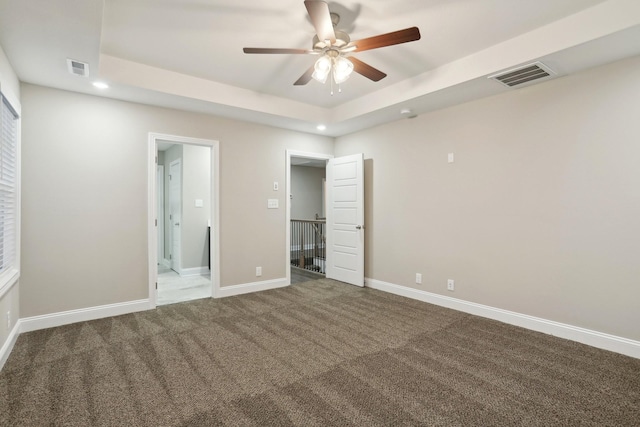 unfurnished bedroom with baseboards, visible vents, a raised ceiling, carpet, and recessed lighting