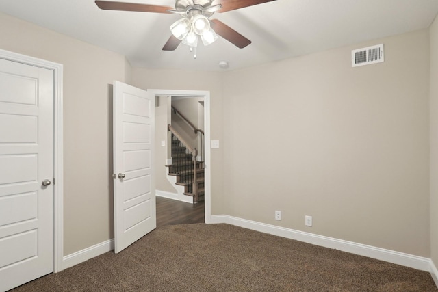 unfurnished room featuring a ceiling fan, visible vents, dark carpet, and baseboards