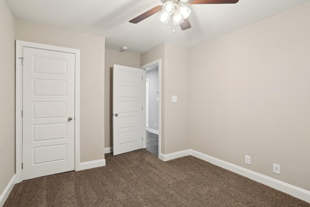 unfurnished bedroom with ceiling fan, dark carpet, and baseboards