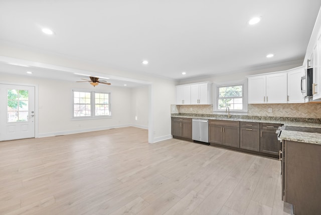 kitchen with decorative backsplash, stainless steel appliances, light wood-type flooring, white cabinetry, and light stone counters