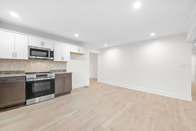 kitchen featuring appliances with stainless steel finishes, light wood-type flooring, decorative backsplash, white cabinets, and ornamental molding