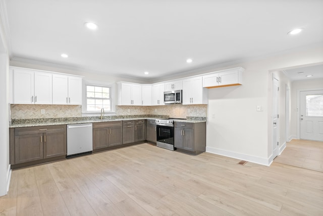 kitchen featuring stainless steel appliances, light hardwood / wood-style flooring, plenty of natural light, and white cabinets