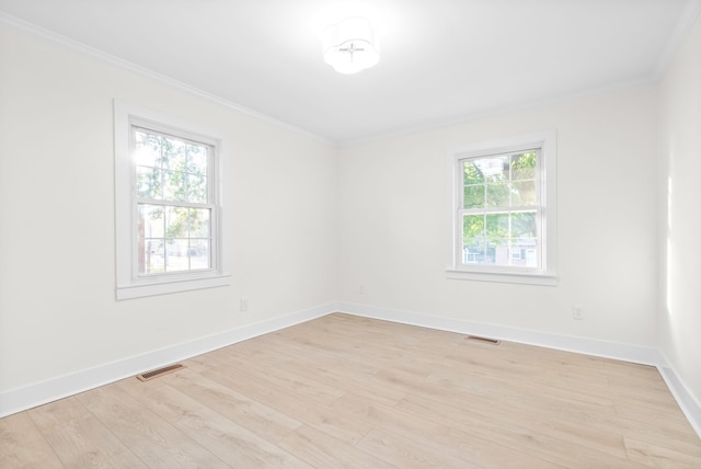 spare room featuring ornamental molding, plenty of natural light, and light wood-type flooring