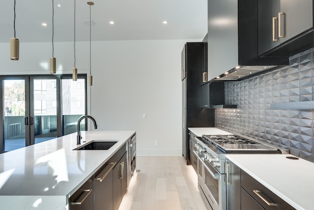 kitchen featuring decorative backsplash, hanging light fixtures, sink, light wood-type flooring, and double oven range