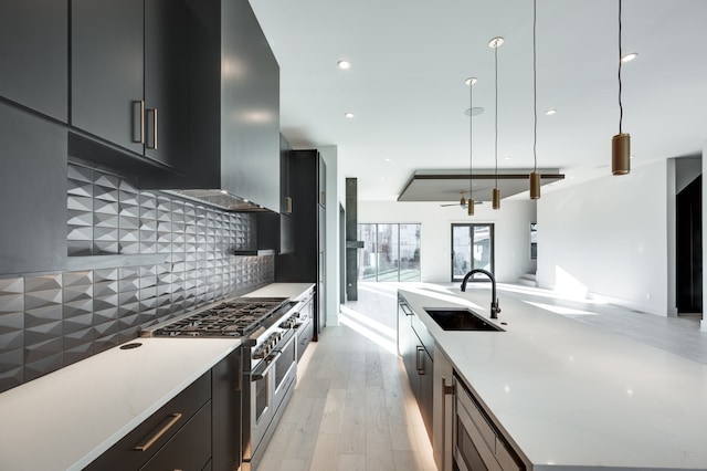 kitchen with decorative backsplash, light hardwood / wood-style flooring, sink, pendant lighting, and stainless steel appliances