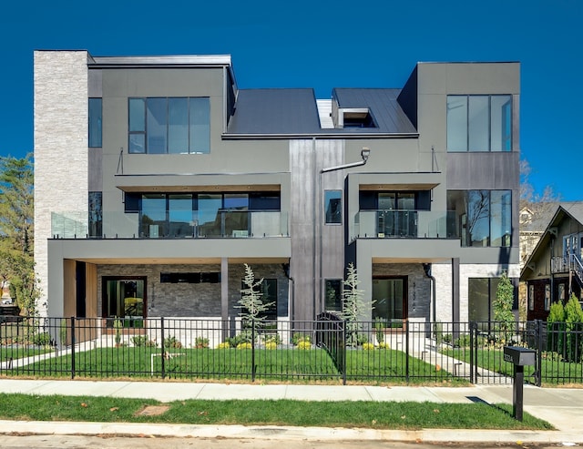 contemporary home featuring a balcony and a front lawn