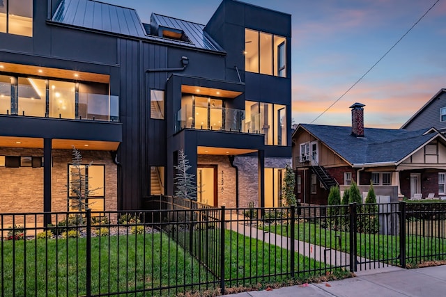 contemporary house featuring a balcony and a yard