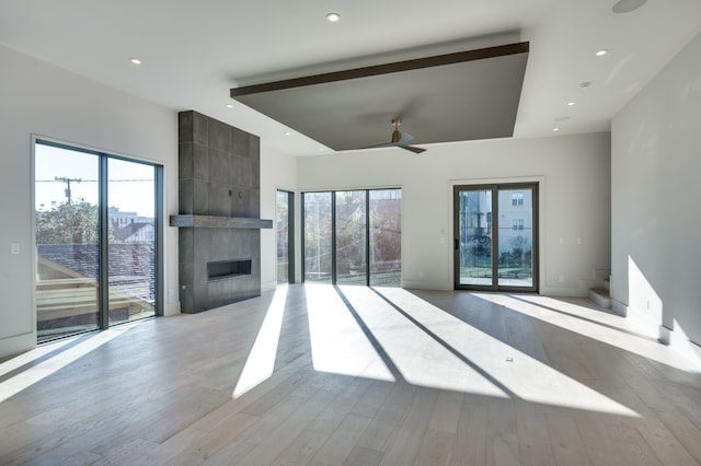 unfurnished living room featuring light wood-type flooring, plenty of natural light, and a tile fireplace