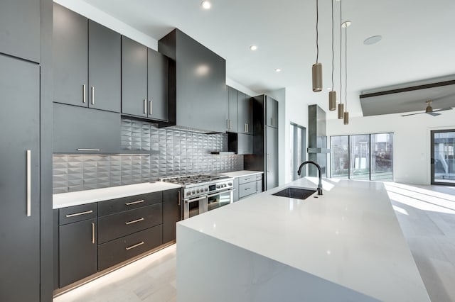 kitchen with extractor fan, range with two ovens, sink, decorative light fixtures, and tasteful backsplash