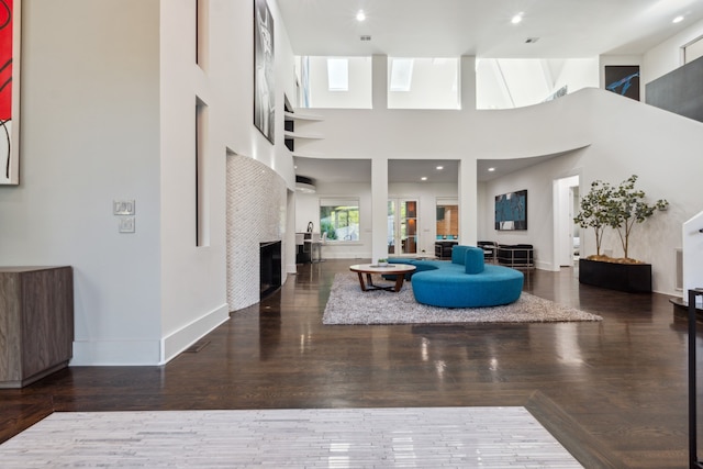 living room with a high ceiling, dark hardwood / wood-style floors, and a skylight