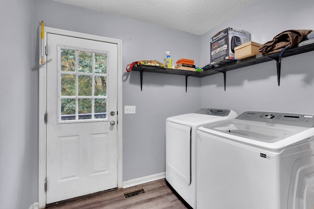 clothes washing area with a textured ceiling, washing machine and dryer, and dark hardwood / wood-style flooring