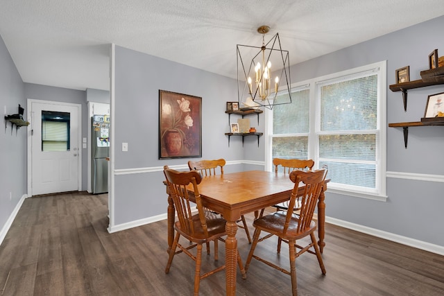 dining area featuring dark wood-type flooring, a notable chandelier, and a textured ceiling