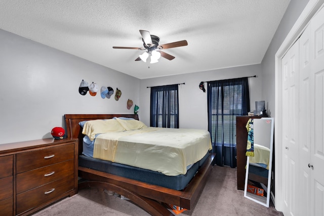 bedroom with a closet, ceiling fan, carpet flooring, and a textured ceiling