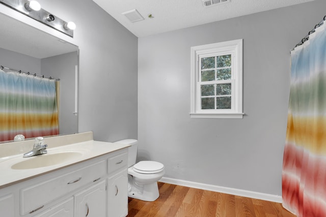 bathroom featuring vanity, toilet, wood-type flooring, and a textured ceiling