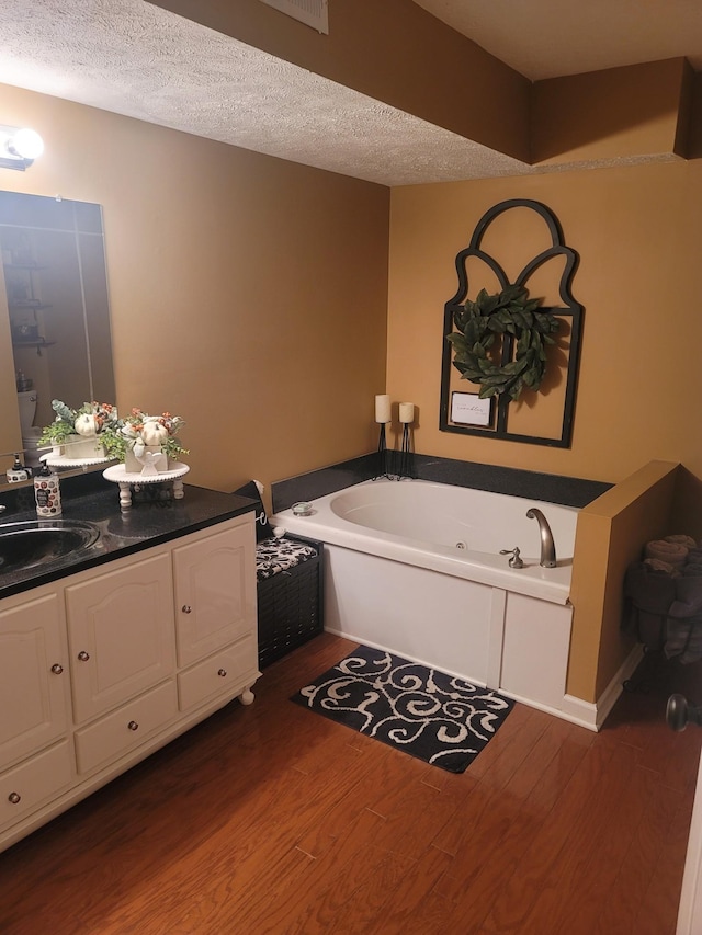 47 Hickory Ln, Sugar Tree, TN 38380 - bathroom featuring wood finished floors, a jetted tub, vanity, and a textured ceiling