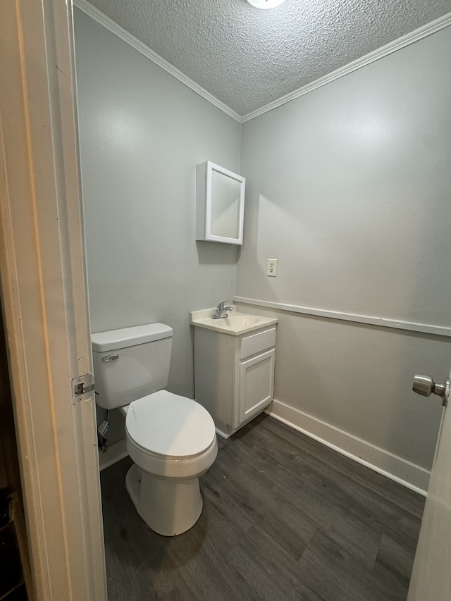 bathroom featuring toilet, wood-type flooring, ornamental molding, and a textured ceiling