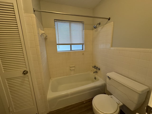 bathroom featuring toilet, tile walls, and tiled shower / bath