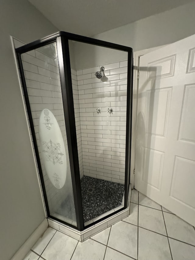 bathroom with a shower with door and tile patterned floors