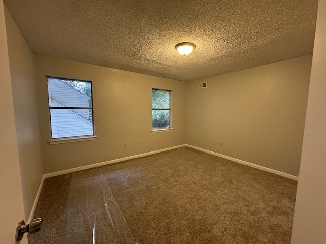 unfurnished room with dark colored carpet and a textured ceiling