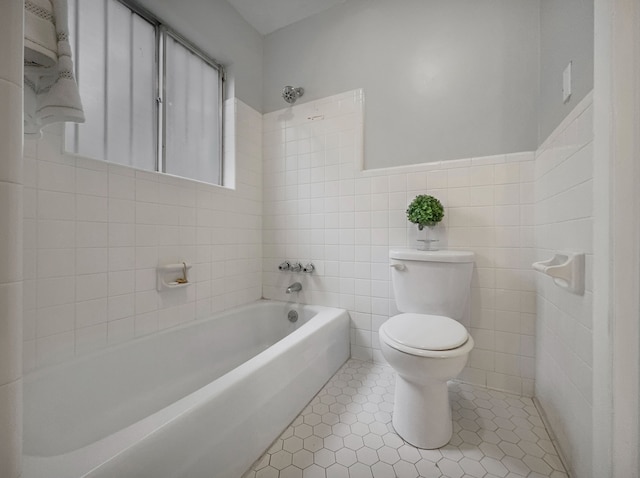 bathroom featuring tile patterned floors, toilet, shower / bathing tub combination, and tile walls