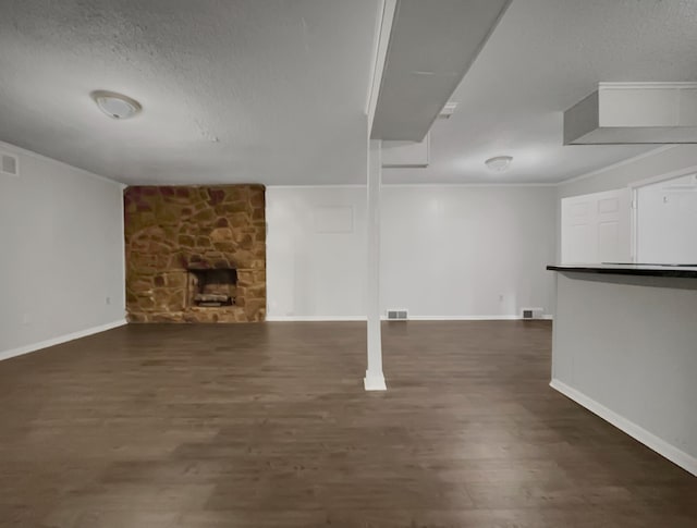 unfurnished living room with dark wood-type flooring, a textured ceiling, and crown molding