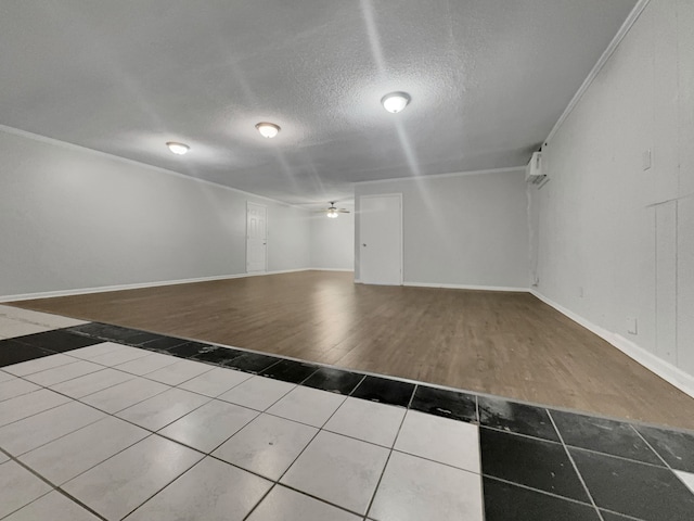 empty room with a wall mounted AC, crown molding, a textured ceiling, hardwood / wood-style floors, and ceiling fan