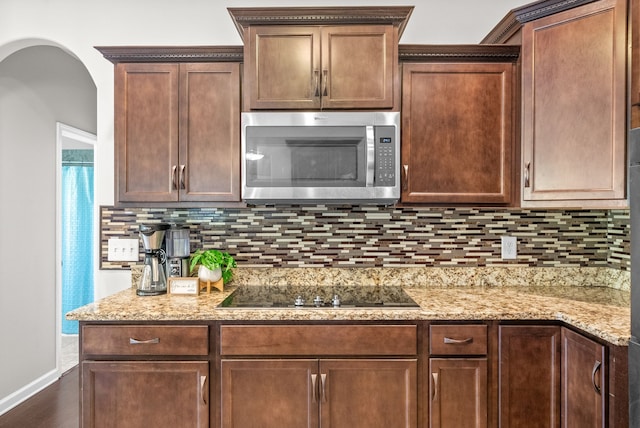 kitchen with light stone counters, hardwood / wood-style flooring, tasteful backsplash, and black electric cooktop