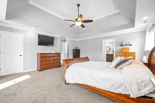 bedroom with ensuite bathroom, a tray ceiling, and ceiling fan