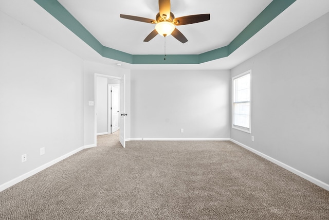 spare room featuring carpet, ceiling fan, and a raised ceiling