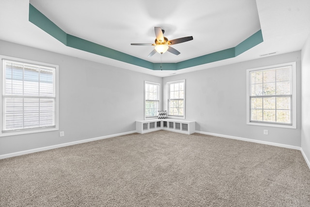 unfurnished room with carpet, a tray ceiling, and ceiling fan