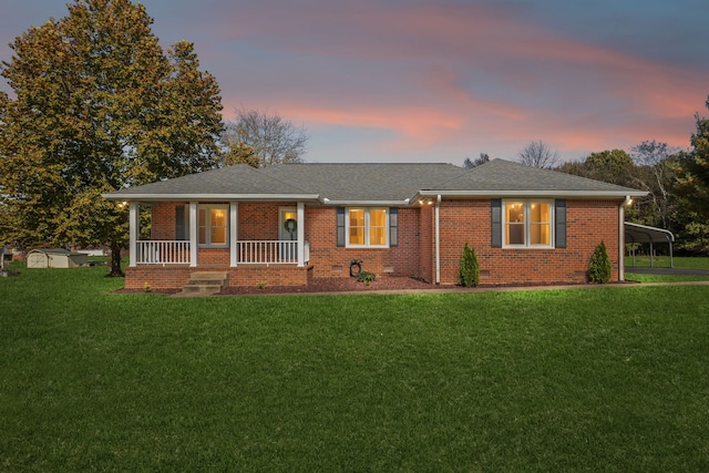 single story home with covered porch, a carport, and a yard