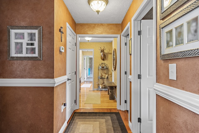 corridor with hardwood / wood-style floors and a textured ceiling