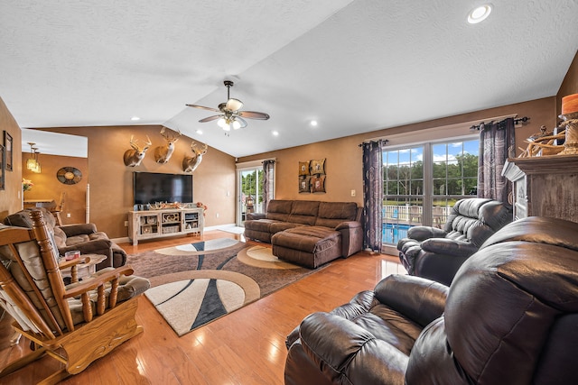 living room with vaulted ceiling, ceiling fan, light hardwood / wood-style floors, and plenty of natural light