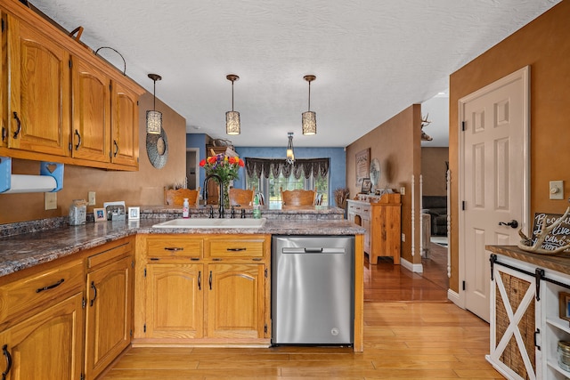 kitchen featuring dishwasher, a textured ceiling, kitchen peninsula, hanging light fixtures, and light hardwood / wood-style flooring