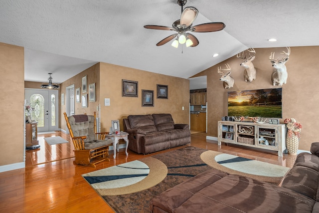 living room with a textured ceiling, hardwood / wood-style flooring, ceiling fan, and vaulted ceiling