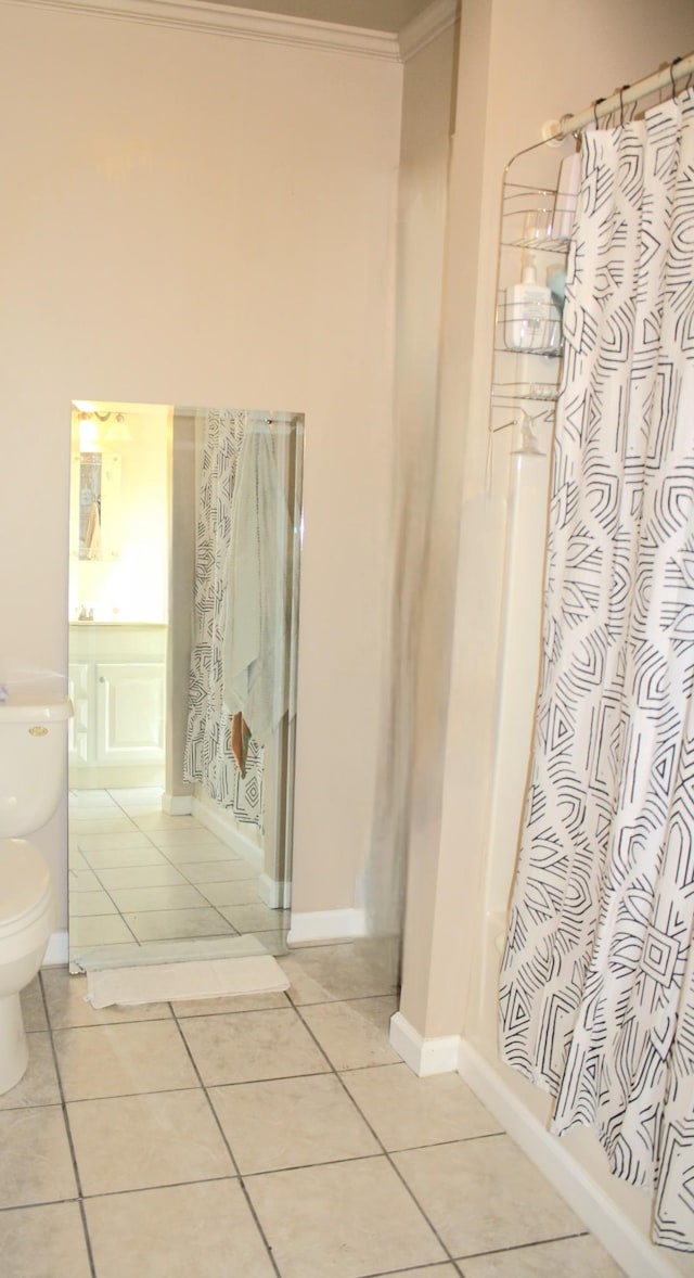 bathroom featuring ornamental molding, toilet, baseboards, tile patterned floors, and a shower with curtain