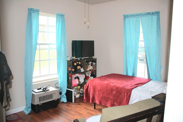 bedroom featuring multiple windows, ornamental molding, and wood finished floors