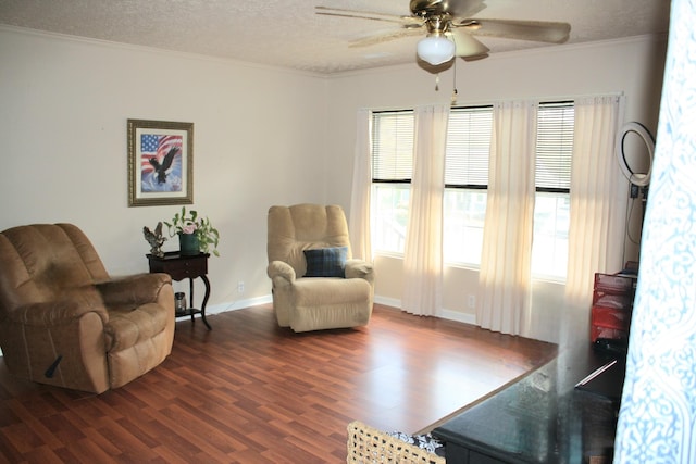 sitting room with ornamental molding, baseboards, ceiling fan, dark wood-style floors, and a textured ceiling
