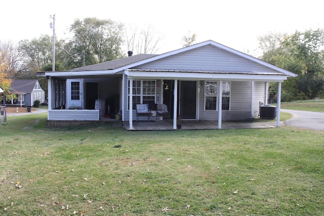 rear view of property with a lawn, central AC unit, and a sunroom