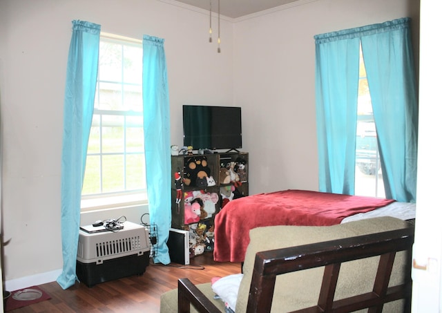 bedroom with ornamental molding and wood finished floors