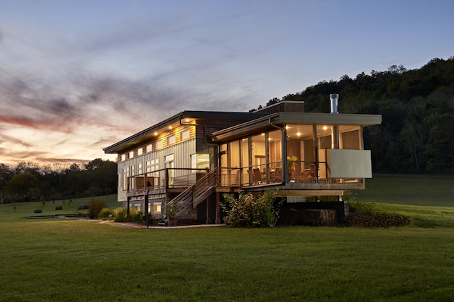 back house at dusk featuring a yard and a wooden deck