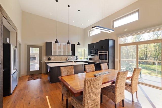 dining room featuring a high ceiling, plenty of natural light, and wood-type flooring