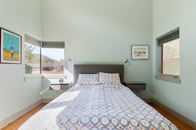 bedroom with a towering ceiling and light wood-type flooring