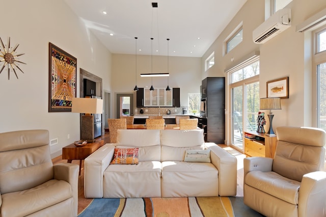 living room featuring a high ceiling, a wealth of natural light, and a wall mounted AC