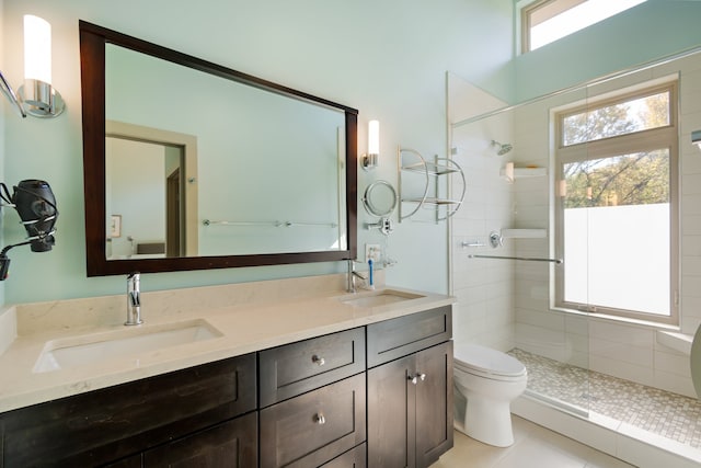 bathroom with tile patterned flooring, toilet, vanity, and tiled shower