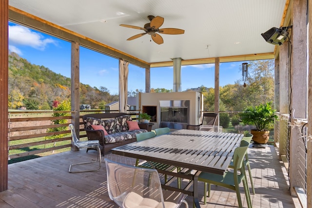 sunroom with a mountain view, ceiling fan, and a healthy amount of sunlight