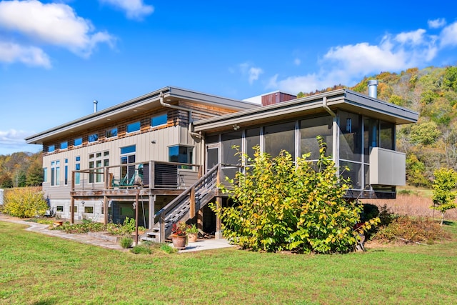 rear view of property with a lawn and a sunroom