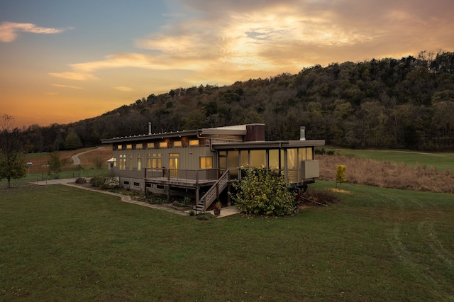 back house at dusk with a lawn