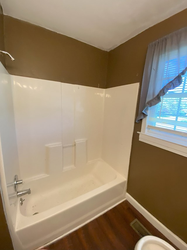 bathroom with toilet, shower / tub combination, and hardwood / wood-style floors