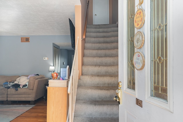 stairway with a textured ceiling and hardwood / wood-style flooring